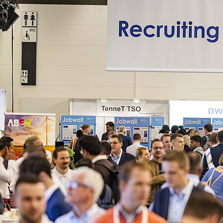 View over the crowd to the recruiting area. A large sign hanging from the ceiling reads Recruiting Forum.