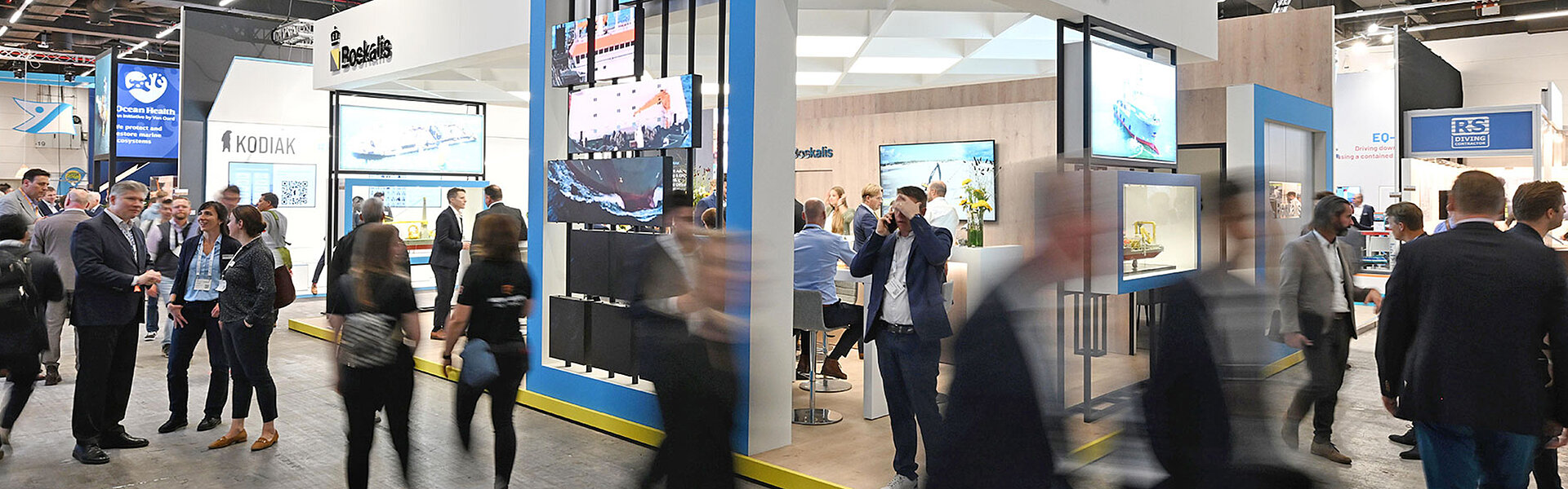 View of the exhibition stands at WindEnergy Hamburg. People walk through the aisles.