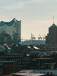 Key visual of the RECHARGE Wind Power Summit. View of the main church St. Michaelis, the Elbphilharmonie concert hall and Hamburg harbour. Wind turbines can be seen in the background.